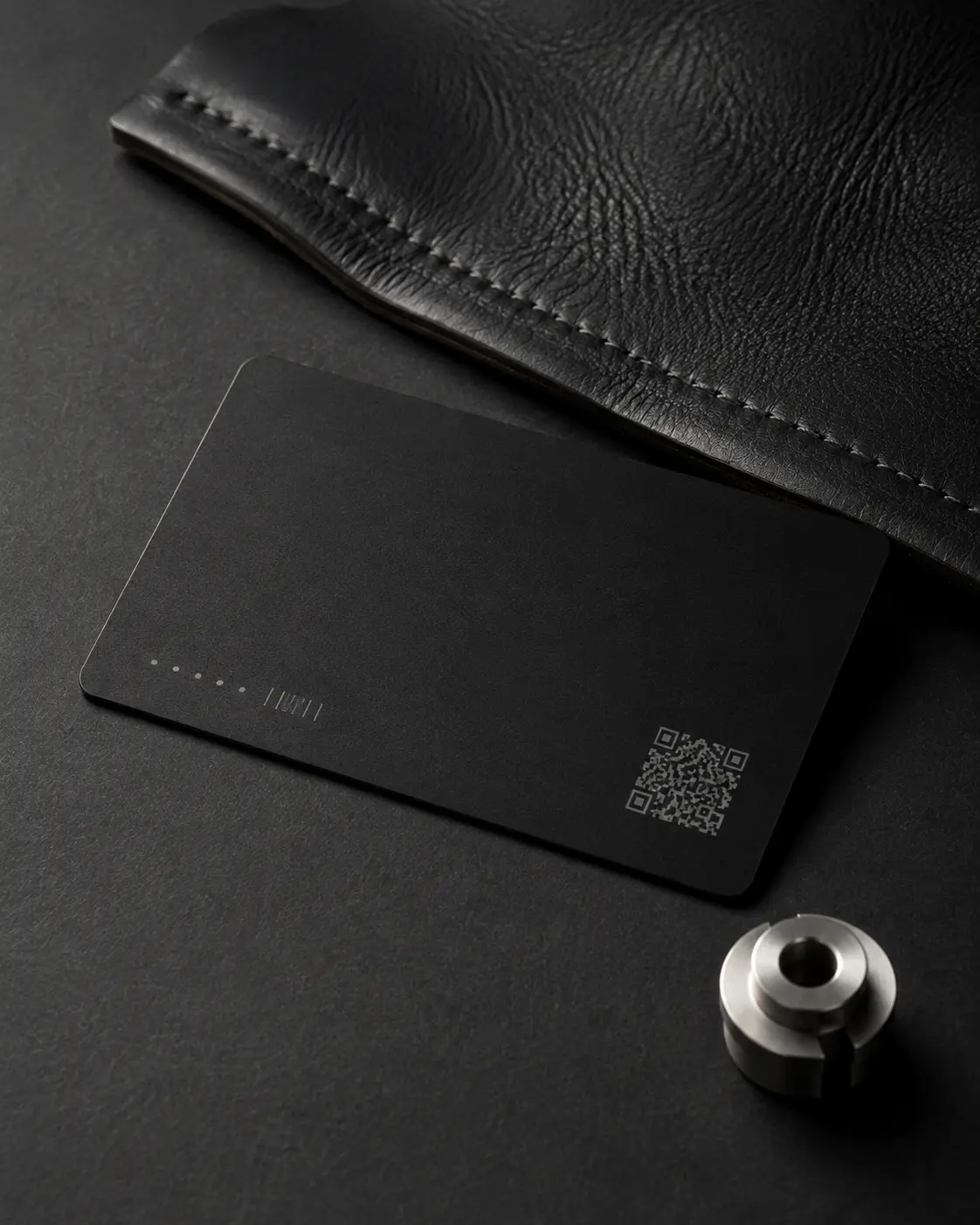 A thin black authenticity card shown with leather and a machined metal component